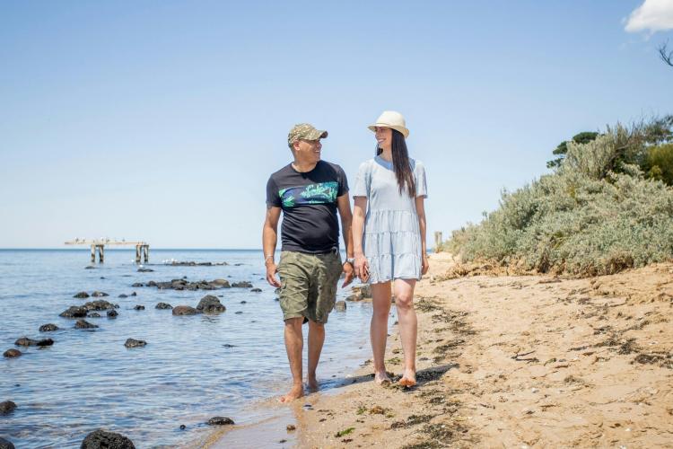 two adults walking barefoot along the beach