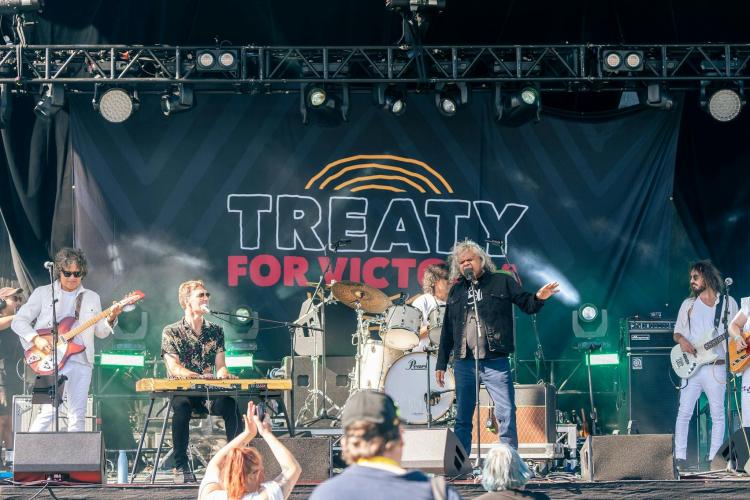 First Nations performer on stage with band and festival crowd in front of stage