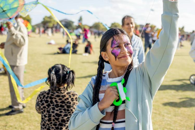 Person with butterfly face paint on smiling and holding a kite string